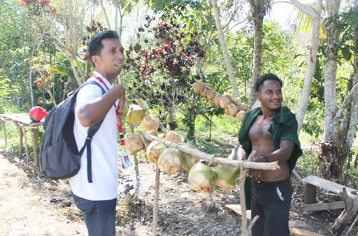 Business opportunity: Radius Monim (right) sells young coconuts in Hansambe hamlet, the last settlement before reaching Telaga Cinta, next to the much larger Lake Sentani.