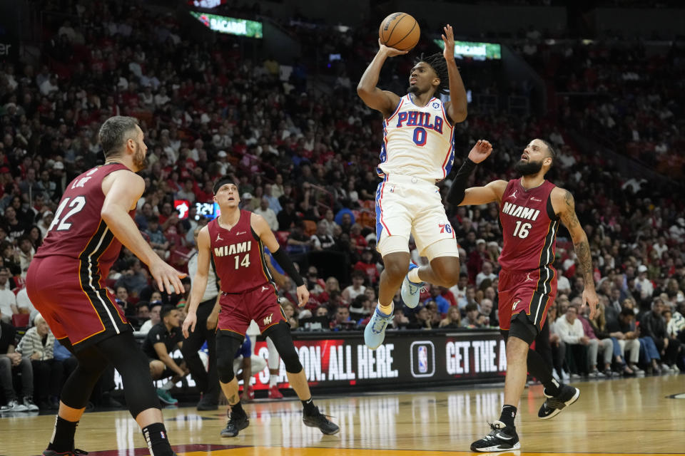 Philadelphia 76ers guard Tyrese Maxey (0) shoots as Miami Heat forward Kevin Love, guard Tyler Herro (14) and forward Caleb Martin (16) defend during the first half of an NBA basketball game, Monday, Dec. 25, 2023, in Miami. (AP Photo/Lynne Sladky)