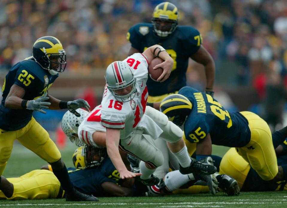 (CR OSUMICH RUSSELL 22NOV03) Ohio State's #16 Craig Krenzel gets knocked down by a swarming Michigan defense in the first half of action at Ann Arbor on Nov 16, 2003. (Dispatch photo by Chris Russell)