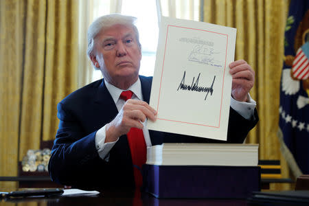 FILE PHOTO: U.S. President Donald Trump displays his signature after signing the $1.5 trillion tax overhaul plan along with a short-term government spending bill in the Oval Office of the White House in Washington, U.S., December 22, 2017. REUTERS/Jonathan Ernst/File Photo