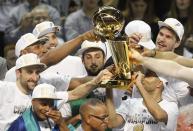 San Antonio Spurs' Patty Mills of Australia (bottom L) cries as teammates hoist the Larry O'Brien trophy after the Spurs defeated the Miami Heat in Game 5 of their NBA Finals basketball series in San Antonio, Texas, June 15, 2014. REUTERS/Mike Stone (UNITED STATES - Tags: SPORT BASKETBALL)