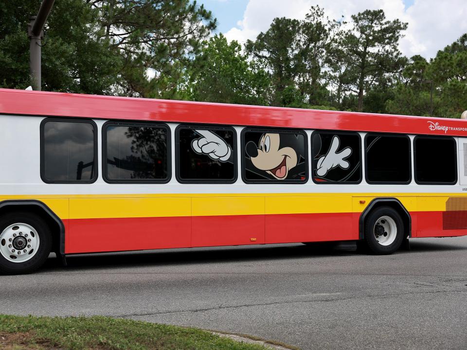 A Disney bus with red and yellow stripes and Mickey on the windows