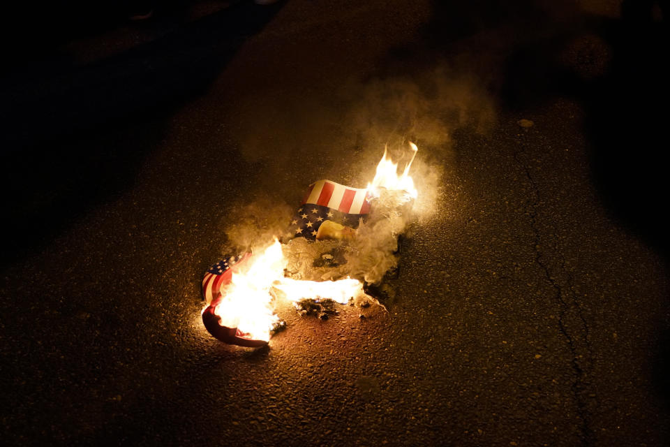 FILE - In this Nov. 14, 2020, file photo, a sign that counter-protesters lit on fire burns after supporters of President Donald Trump held pro-Trump marches Saturday, in Washington. Reports of hateful and violent speech on Facebook poured in on the night of May 28 after President Donald Trump hit send on a social media post warning that looters who joined protests following Floyd's death last year would be shot, according to internal Facebook documents shared with The Associated Press. (AP Photo/Julio Cortez, File)