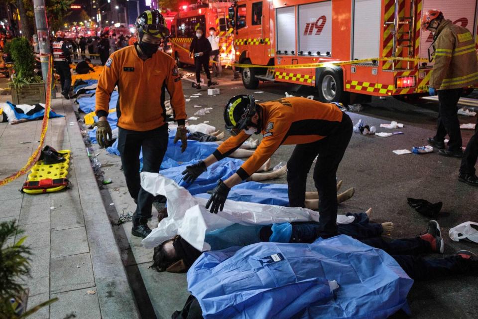 Emergency workers pull sheets over bodies in the street.