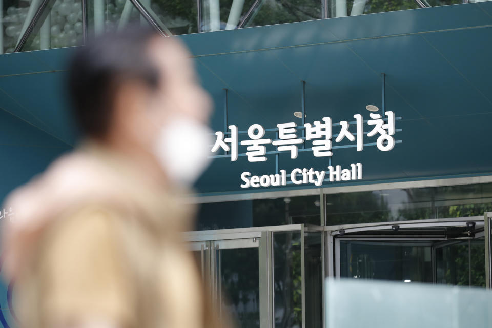 A man wearing a face mask walks near Seoul City Hall in Seoul, South Korea, Wednesday, July 15, 2020. The city government of the South Korean capital, Seoul, said Wednesday it will launch an investigation into allegations of sexual misconduct surrounding late Mayor Park Won-soon, who was found dead after one of his secretaries filed a complaint claiming yearslong abuse. (AP Photo/Lee Jin-man)