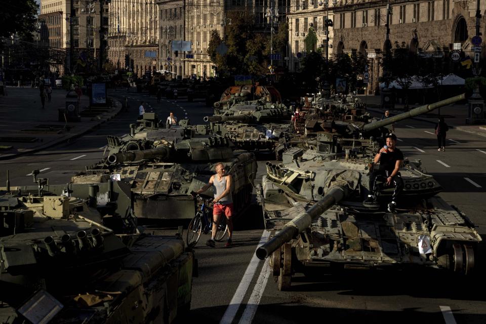 People walk around destroyed Russian military vehicles installed in downtown Kyiv, Ukraine, Wednesday, Aug. 24, 2022. (AP Photo/Evgeniy Maloletka)