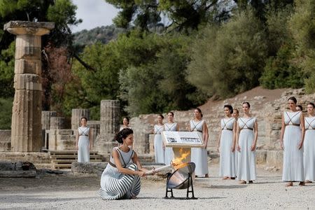 Olympics - Dress Rehearsal - Lighting Ceremony of the Olympic Flame Pyeongchang 2018 - Ancient Olympia, Olympia, Greece - October 23, 2017 Greek actress Katerina Lehou, playing the role of High Priestess, lights a torch from the sun's rays reflected in a parabolic mirror during the dress rehearsal for the Olympic flame lighting ceremony for the Pyeongchang 2018 Winter Olympic Games at the site of ancient Olympia in Greece REUTERS/Alkis Konstantinidis