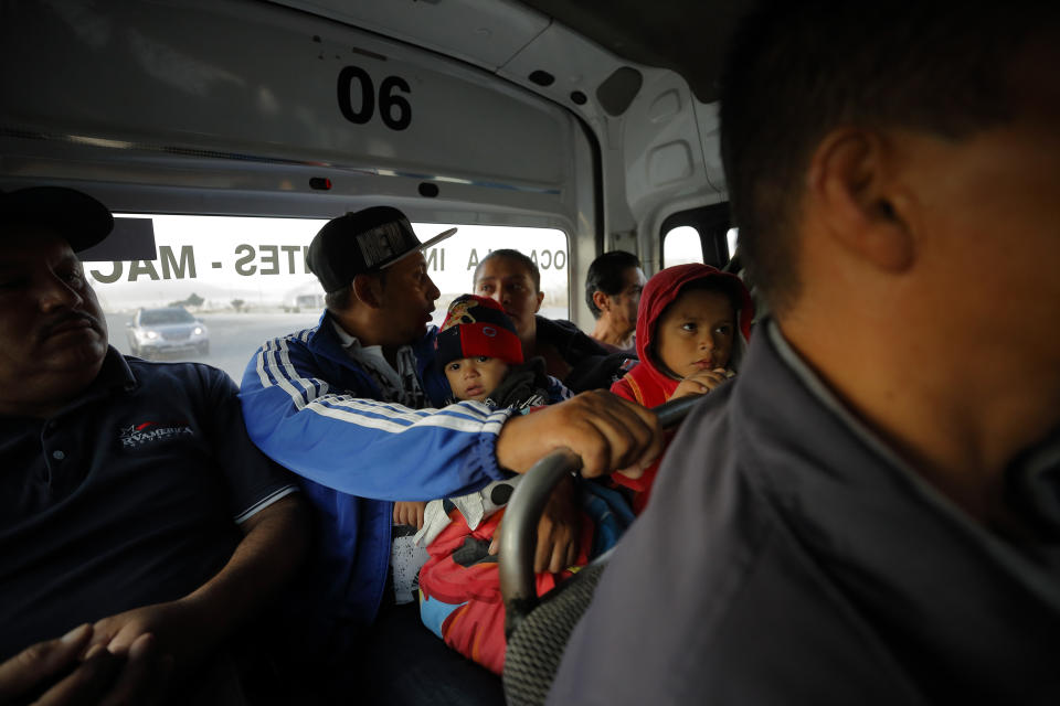 In this July 10, 2019, photo, Juan Carlos Perla, center, talks to his wife, Ruth Aracely Monroy, center right, as they take a bus from their home in Tijuana, Mexico, for an asylum hearing in San Diego. The Perla family of El Salvador has slipped into a daily rhythm in Mexico while they wait for the U.S. to decide if they will win asylum. (AP Photo/Gregory Bull)