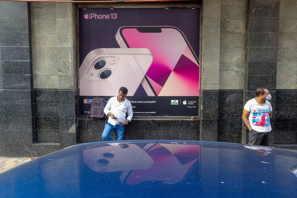 People are seen in front of an iPhone 13 advertisement , outside a store in Kolkata , India , on 29 October 2021 . Apple CEO has announced that the company has gained 29% in sales in last quarter , owing to festive season in India . (Photo by Debarchan Chatterjee/NurPhoto via Getty Images)