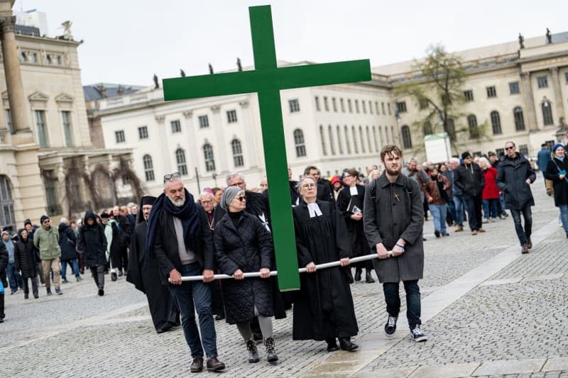 Worshippers carry a green cross across Bebel square in Berlin, during the Good Friday procession of St. Mary's Church. Fabian Sommer/dpa