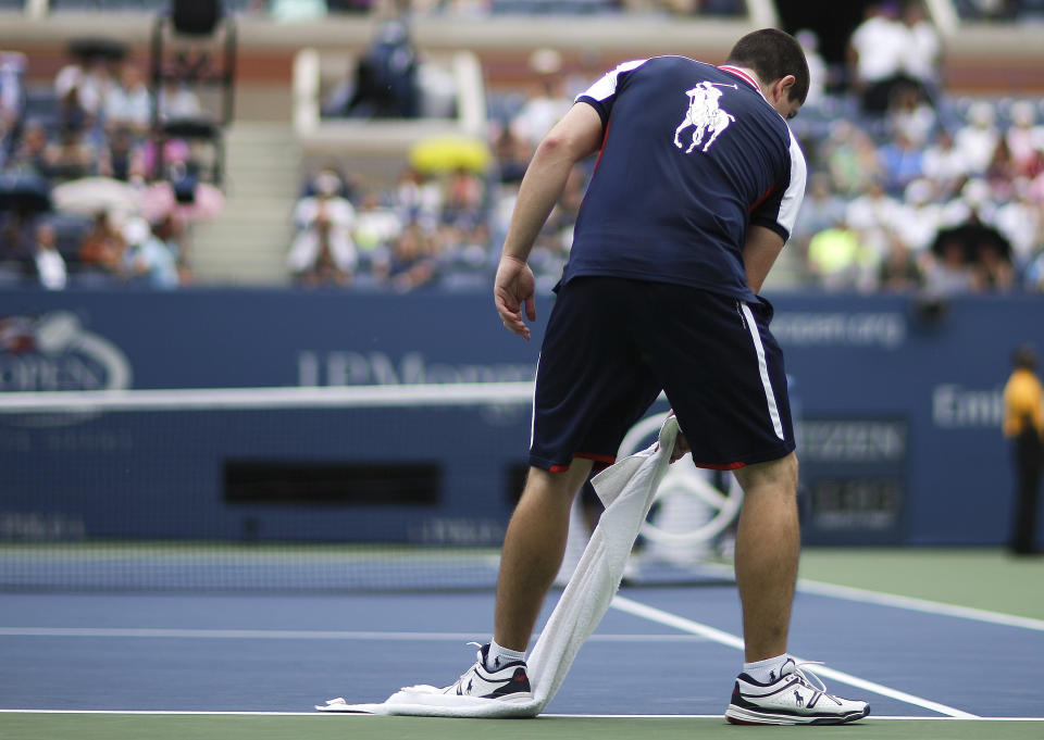 A ball runner dries the lines on the court during brief rain delay of the first round match between Rafael Nadal of Spain and Ryan Harrison at the 2013 U.S. Open tennis tournament Monday, Aug. 26, 2013, in New York. (AP Photo/David Goldman)