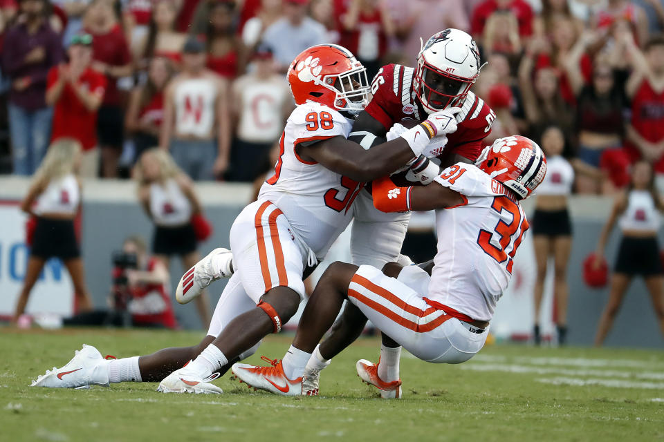 FILE - Clemson's Mario Goodrich (31) and Myles Murphy (98) tie up North Carolina State's Emeka Emezie (86) during the second half of an NCAA college football game in Raleigh, N.C., Saturday, Sept. 25, 2021. Clemson had won six straight ACC titles heading into last season, but started 4-3 and fell out of contention for a seventh. The team rebounded, though, to win their last six games — the longest current win streak among Power Five teams — and look to a slimmer, more confident quarterback DJ Uiagalelei to start a new championship run. (AP Photo/Karl B DeBlaker, File)