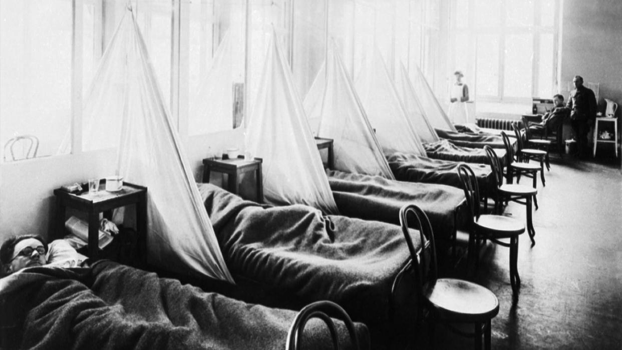  Black and white photo of a row of beds in a 1918 flu pandemic ward during World War I. 