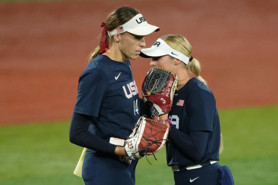 Team United States utility Allyson Carda (3) hands pitcher Monica Abbott (14) the ball and talks during a pitching change against Japan during the fifth inning in the gold medal game of the Tokyo Olympics.