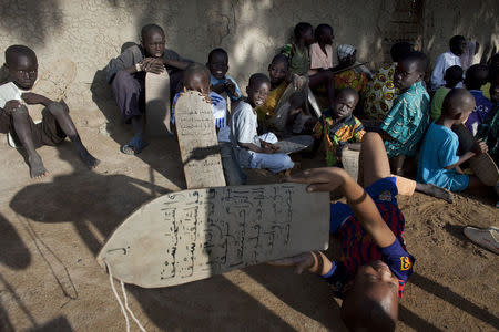 Boys recite Quranic verses handwritten on pieces of wood during a religious class in front of the Grand Mosque of Djenne, Mali September 1, 2012. REUTERS/Joe Penney