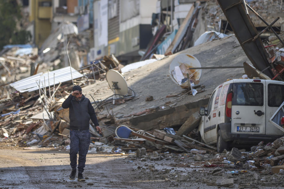A man walks past debris from destroyed buildings in Antakya, southeastern Turkey, Tuesday, Feb. 21, 2023. The death toll in Turkey and Syria rose to eight in a new and powerful earthquake that struck two weeks after a devastating temblor killed nearly 45,000 people, authorities and media said Tuesday. (AP Photo/Unal Cam)