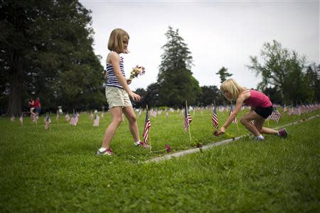 Sisters Rachel (L), 7, and Brooke, 6, Masenheimer place flowers on the grave sites of Battle of Gettysburg soldiers during a ceremony at National Soldier's Cemetery following the Gettysburg Memorial Day parade in Gettysburg, Pennsylvania, May 26, 2014. REUTERS/Mark Makela