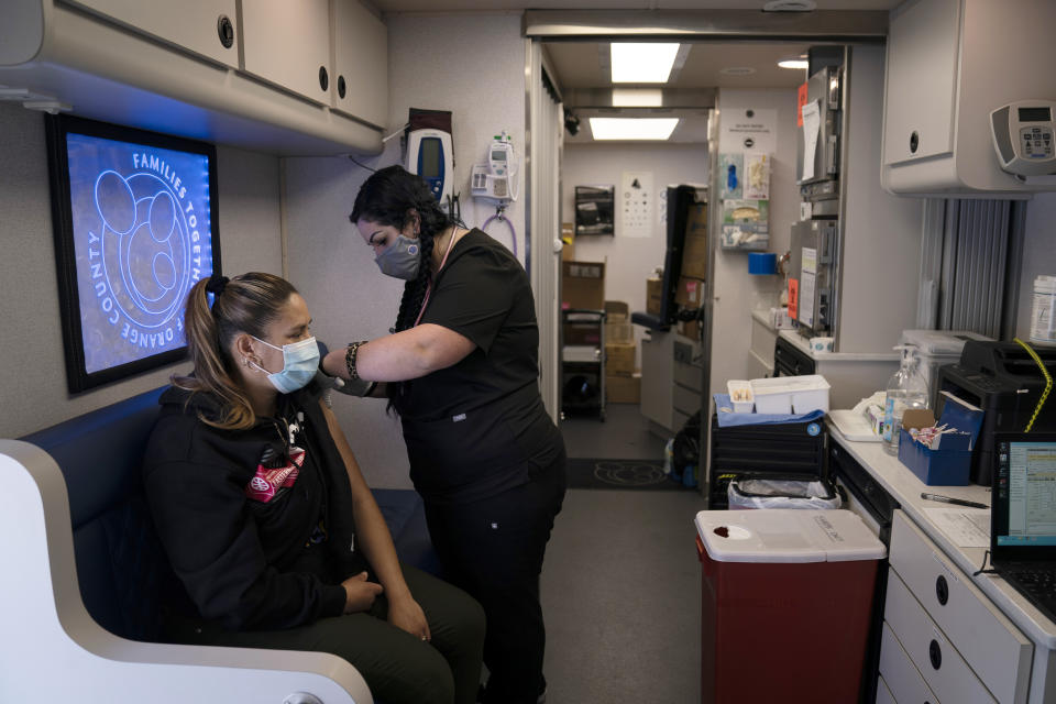 FILE - In this April 29, 2021, file photo, nurse Natasha Garcia administers a dose of the Moderna COVID-19 vaccine to Monica Villalobos in a mobile clinic set up in the parking lot of a shopping center in Orange, Calif. COVID-19 deaths in the U.S. have tumbled to an average of just over 600 per day — the lowest level in 10 months — with the number of lives lost dropping to single digits in well over half the states and hitting zero on some days. (AP Photo/Jae C. Hong, File)