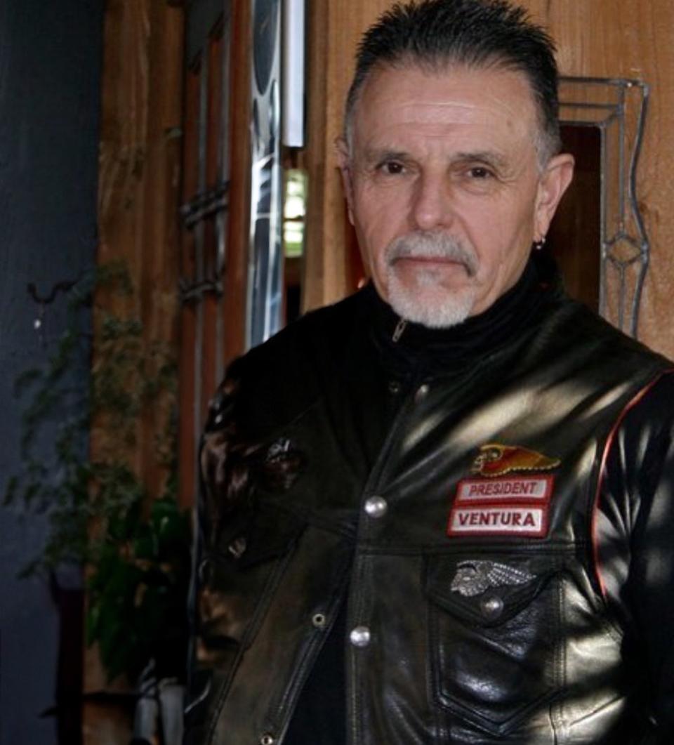 George Christie standing up wearing a black leather jacket