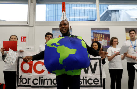 Environmental activists display signs inside the venue of the COP24 U.N. Climate Change Conference 2018 in Katowice, Poland, December 4, 2018