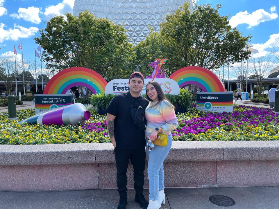 josie and her partner posing for a photo in front of the epcot ball in disney world