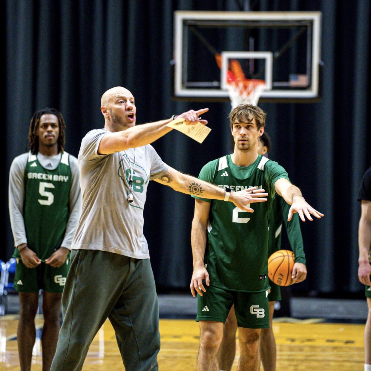 UWGB coach Sundance Wicks gives instructions while guard Preston Ruedinger (2) looks on.