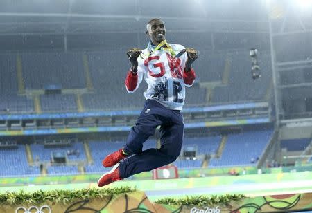 2016 Rio Olympics - Athletics - Final - Men's 5000m Final - Olympic Stadium - Rio de Janeiro, Brazil - 20/08/2016. Gold winner Mohamed Farah (GBR) of Britain celebrates and dances in the rain. REUTERS/Stoyan Nenov