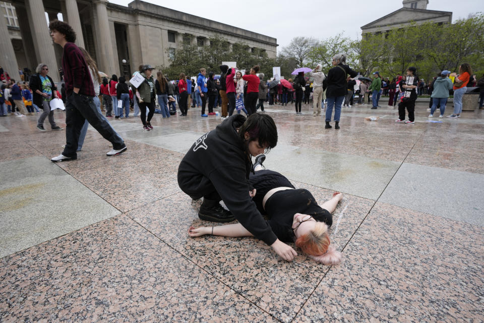 Robin Casler draws a chalk outline around Noah Williams at the March for Our Lives anti gun protest outside the State Capitol in Nashville, Tenn., on Monday, April 3, 2023. (AP Photo/George Walker IV)