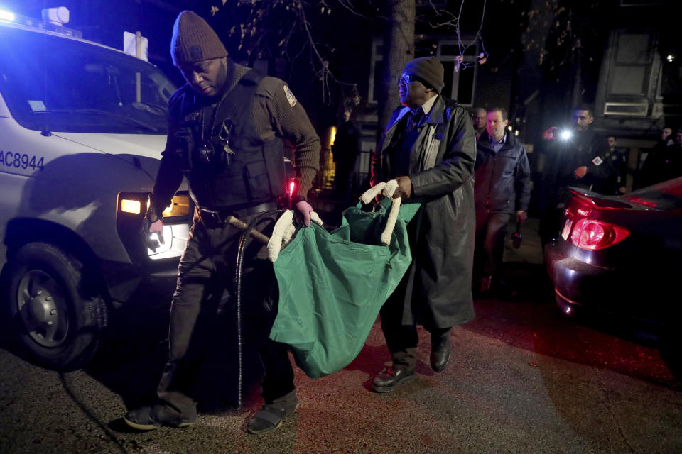 A Chicago police officer and a Chicago Animal Care and Control worker carry a coyote out in a green bag after tranquilizing the animal behind a home on Thursday, Jan. 9, 2020. Authorities on the hunt for coyotes in downtown Chicago after two reported attacks, including one where passersby said they had to pull a wild canine off of a 6-year-old boy who was bitten in the head, captured one animal Thursday night on the city's North Side.(Chris Sweda/Chicago Tribune via AP)