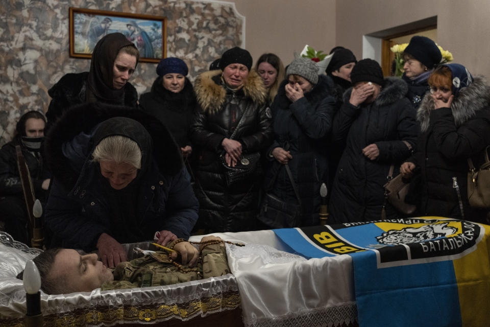 Relatives and friends mourn the body of senior police sergeant Roman Rushchyshyn in the village of Soposhyn, outskirts of Lviv, western Ukraine, Thursday, March 10, 2022, in Lviv. Rushchyshyn, a member of the Lviv Special Police Patrol Battalion, was killed in the Luhansk Region. Temporary cease-fires to allow evacuations and humanitarian aid have repeatedly faltered, with Ukraine accusing Russia of continuing its bombardments. (AP Photo/Bernat Armangue)