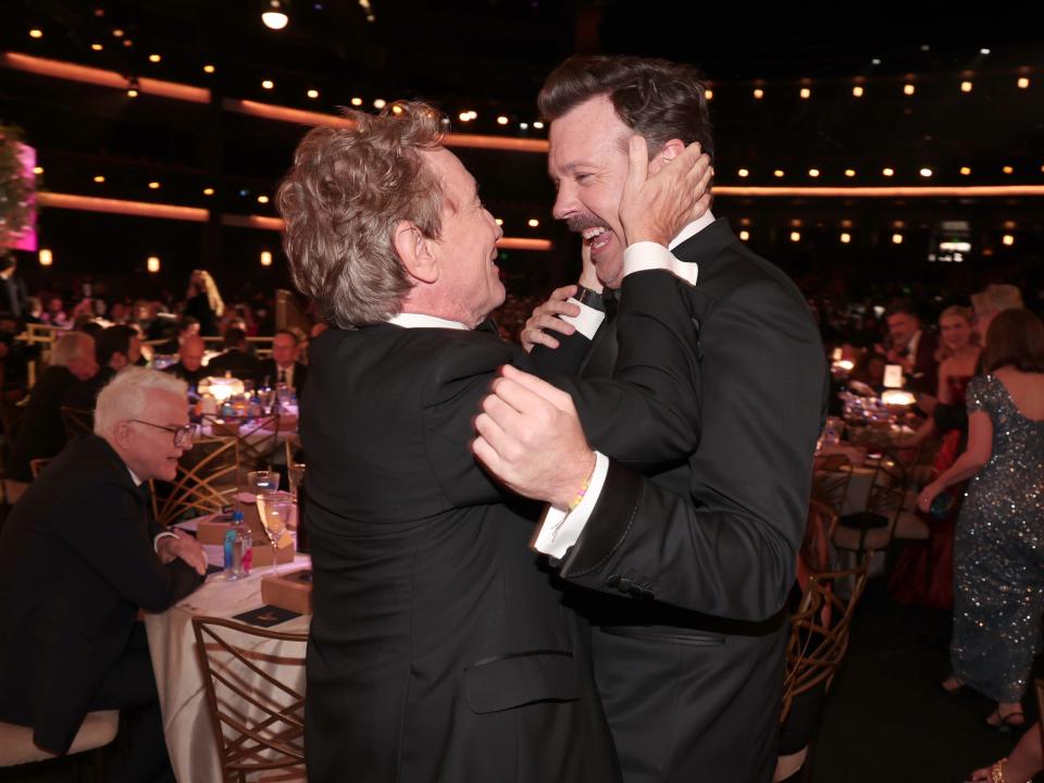 martin short grasps jason sudeikis' face, with both men grinning widely