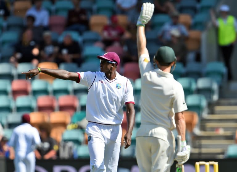 West Indies captain Jason Holder (L) moves his field as Australian batsman Adam Voges (R) asks for the sightscreen to be moved on the first day of the first Test in Hobart on December 10, 2015