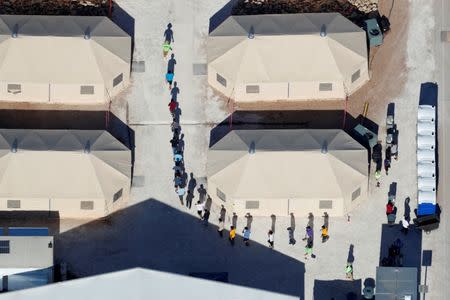 FILE PHOTO - Immigrant children, many of whom have been separated from their parents under a new "zero tolerance" policy by the Trump administration, are shown walking in single file between tents in their compound next to the Mexican border in Tornillo, Texas. REUTERS/Mike Blake