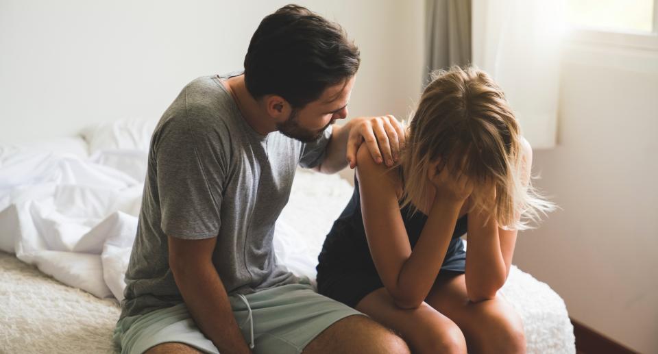 Man consoles upset woman on edge of bed. (Getty Images)