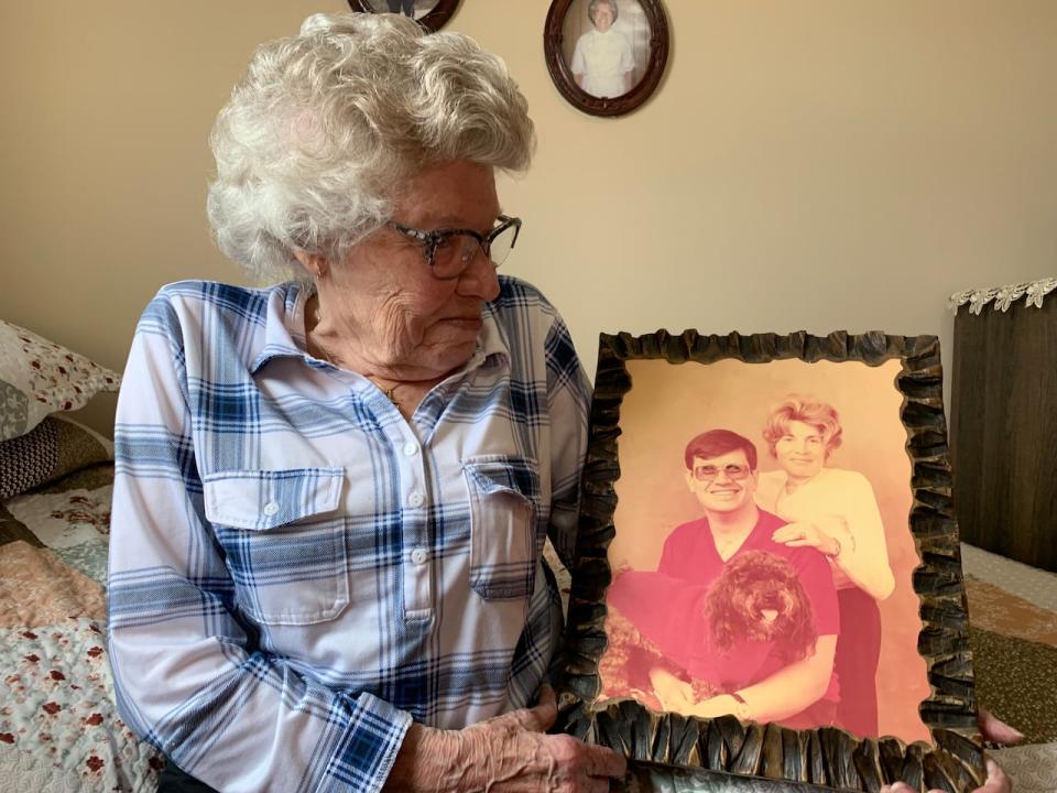 Loretta Burrell holds an old photo portrait of her and her husband with their dog.