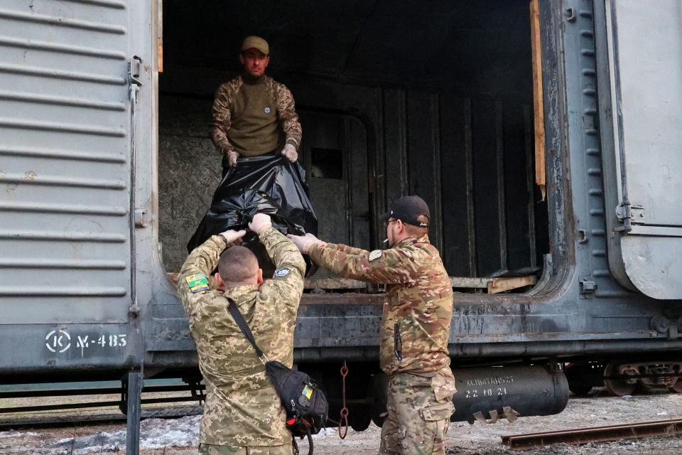 EDITORS NOTE: Graphic content / Members of the Civil-Military Cooperation team load the remains of a Russian soldier into a railroad car in the village of Synykha, Kharkiv region, on April 8, 2023, amid the Russian invasion of Ukraine. (Photo by Sergiy KOZLOV / AFP) (Photo by SERGIY KOZLOV/AFP via Getty Images)