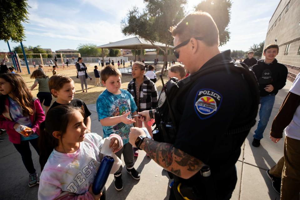 Officer Jessica McCloskey hands out stickers to second graders during recess at Sunset Hills Elementary School on Nov. 30, 2023.