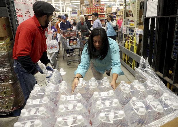 H-E-B employees remove bottles of water from a crate to hand out to customers Thursday morning, Dec. 15, 2016, in Corpus Christi, Texas. The city is warning its 320,000 residents not to use tap water because it might be contaminated with petroleum-based chemicals, prompting a rush on bottled water and the closure of local schools. (Gabe Hernandez/Corpus Christi Caller-Times via AP)