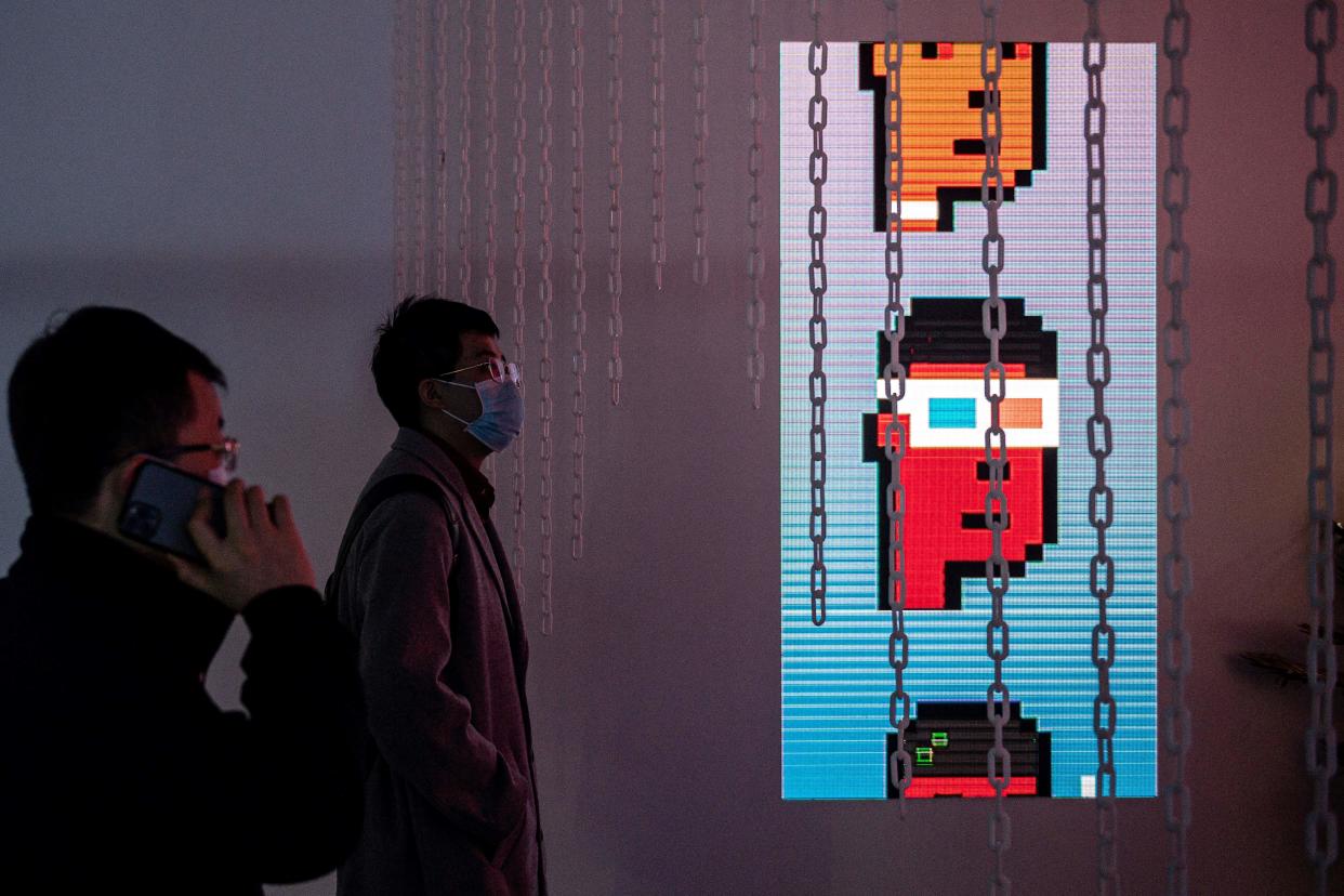 People look at CryptoPunks digital characters (R) at a crypto art exhibition entitled Virtual Niche: Have You Ever Seen Memes in the Mirror?, one of the world's first physical museum shows of blockchain art, ahead of its opening in Beijing on March 26, 2021. - RESTRICTED TO EDITORIAL USE - MANDATORY MENTION OF THE ARTIST UPON PUBLICATION - TO ILLUSTRATE THE EVENT AS SPECIFIED IN THE CAPTION (Photo by NICOLAS ASFOURI / AFP) / RESTRICTED TO EDITORIAL USE - MANDATORY MENTION OF THE ARTIST UPON PUBLICATION - TO ILLUSTRATE THE EVENT AS SPECIFIED IN THE CAPTION / RESTRICTED TO EDITORIAL USE - MANDATORY MENTION OF THE ARTIST UPON PUBLICATION - TO ILLUSTRATE THE EVENT AS SPECIFIED IN THE CAPTION (Photo by NICOLAS ASFOURI/AFP via Getty Images)