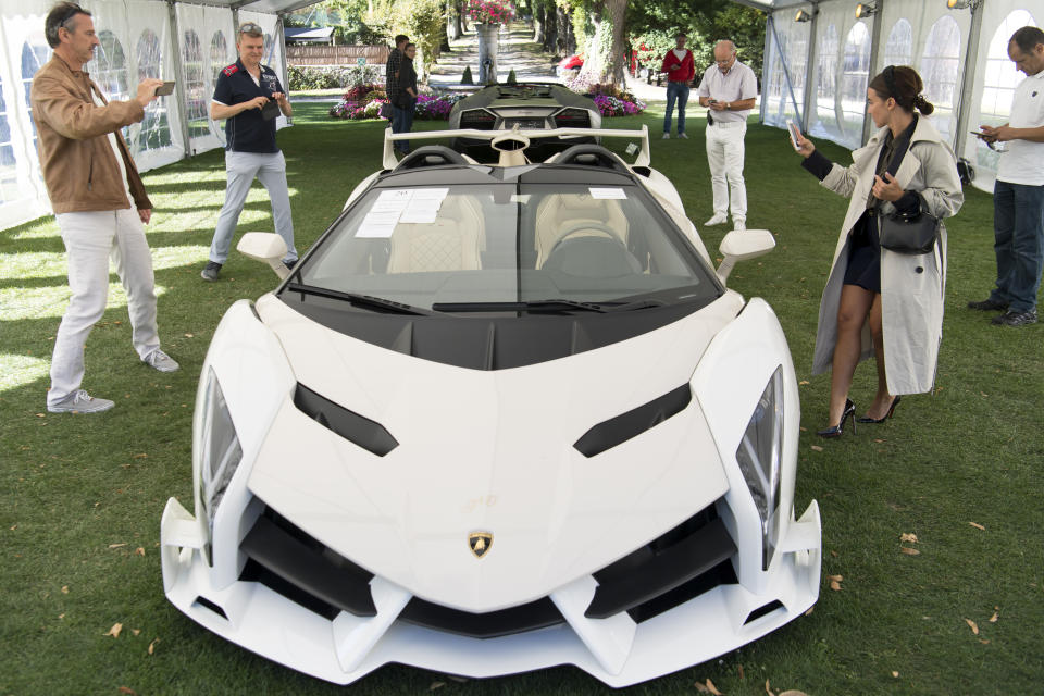 Unas personas observan un Lamborghini Veneno Roadster 2014, que forma parte de unos 25 automóviles lujosos que eran propiedad de Teodoro Nguema Obiang Mangue, hijo del presidente de Guinea Ecuatorial Teodoro Obiang, previo a una subasta de Bonhams en un club de golf en Ginebra, Suiza, el domingo 29 de septiembre de 2019. (Laurent Gillieron/Keystone vía AP)