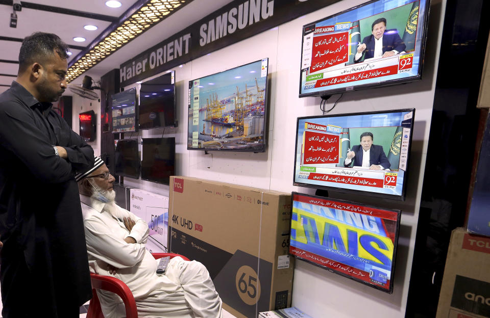 People watch a live address to the nation by Pakistan's Prime Minister Imran Khan, at a shop in Karachi, Pakistan, Thursday, March 4, 2021. Khan on Thursday announced he would seek a vote of confidence from the National Assembly this weekend to prove he still has the support of majority lawmakers in the house, despite the surprising and embarrassing defeat of his ruling party's key candidate in Senate's elections. (AP Photo/Fareed Khan)