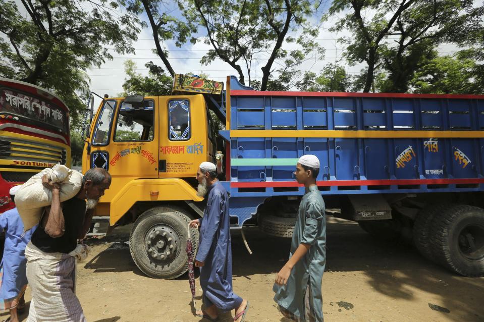 Rohingya refugees walk past trucks that were brought to take them to the Myanmar border outside Nayapara Rohingya refugee camp in Cox's Bazar, Bangladesh, Thursday, Aug.22, 2019. Bangladesh's refugee commissioner said Thursday that no Rohingya Muslims turned up to return to Myanmar from camps in the South Asian nation. (AP Photo/Mahmud Hossain Opu)