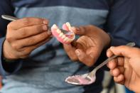 Street dentist Imran Pasha prepares a new set of dentures for a customer at a roadside stall at K.R. Market bus stand in Bangalore