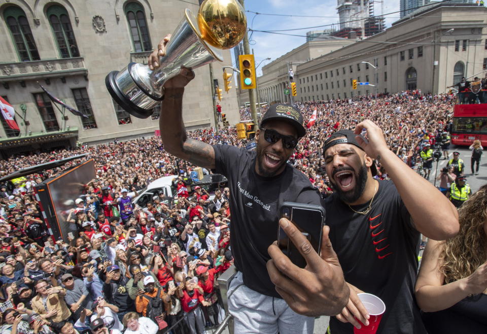 Toronto Raptors' Kawhi Leonard holds his MVP trophy while celebrating with rapper/producer Drake during the team's NBA basketball championship parade in Toronto, Monday, June 17, 2019. (Frank Gunn/The Canadian Press via AP)