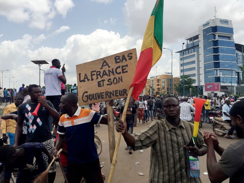 Opposition supporters react to the news of possible military mutiny, at Independence Square in Bamako