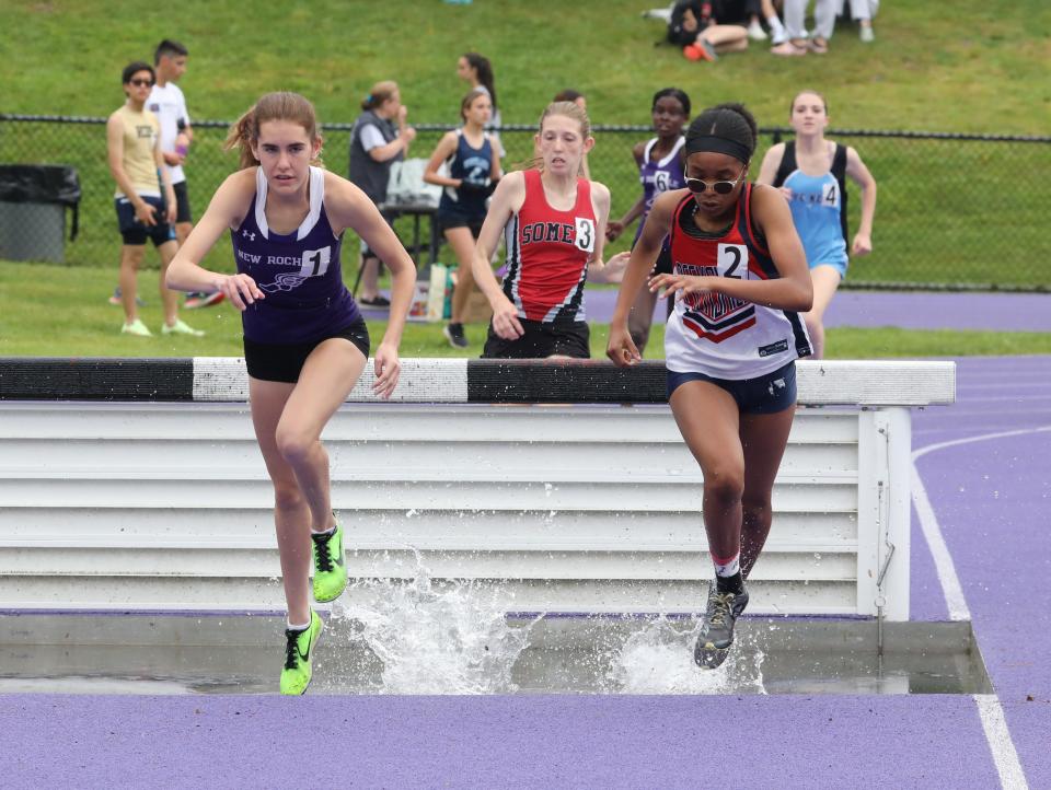 New Rochelle's Kaitlyn Casas (l) and Peekskill's Brianna Carter (r) go through the water during the girls 2,000-meter steeplechase competition during day 2 of the Westchester County Track & Field Championships held at John Jay High School in Cross River, May 21, 2022. Casas finished first and Carter was second.