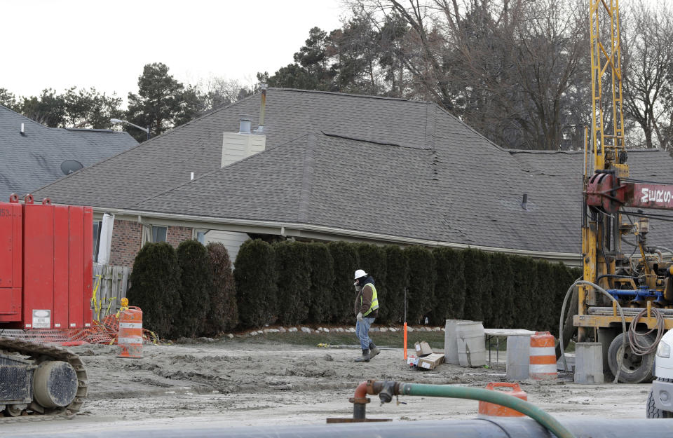 FILE - In this Jan. 4, 2017 file photo, a construction worker walks by a home collapsed by a sinkhole in Fraser, Mich. Officials said Wednesday, Jan. 9, 2019, that the sinkhole north of Detroit that damaged homes and cost $75 million to fix was caused by human error that allowed the quick release of waste and water into a sewer line. The pipe collapsed and caused the Dec. 24, 2016, sinkhole which grew to football field-size. (AP Photo/Carlos Osorio, File)