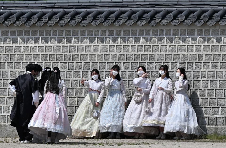 Visitors wearing traditional hanbok dress pose for photos at the Gyeongbokgung Palace in Seoul on May 2, 2022, after South Korea lifted its outdoor mask mandate in response to a steady drop in Covid-19 cases.