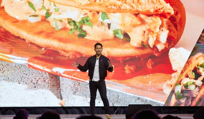 A man standing in front of a giant phot of a taco