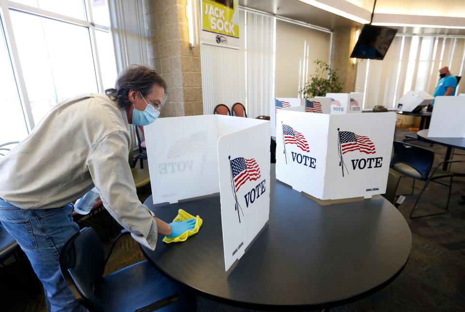 Election judge Matthew Decocq sanitizes a voting booth at the Cooper Tennis Complex polling location on Tuesday, Nov. 3, 2020. 